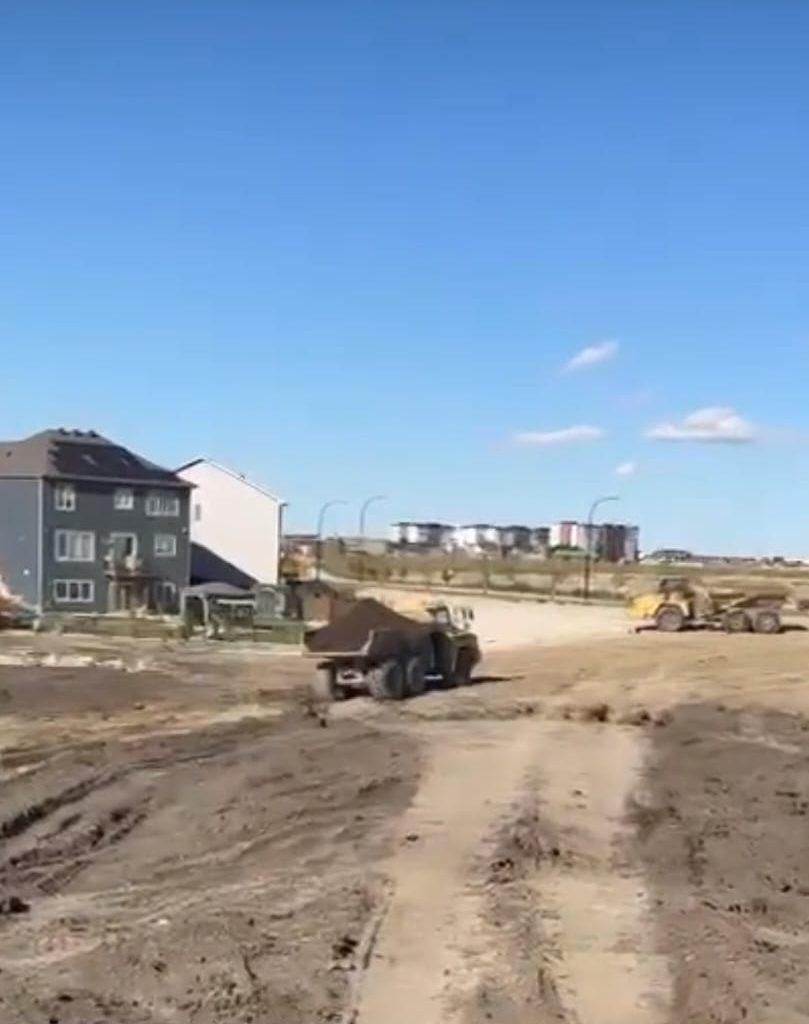 Haul trucks beside new homes
