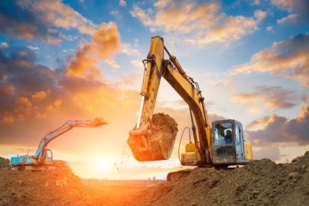 excavator in construction site on sunset sky background