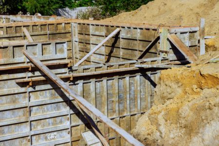 Several pieces of metal formwork have been assembled in preparation for pouring concrete to construct house foundation